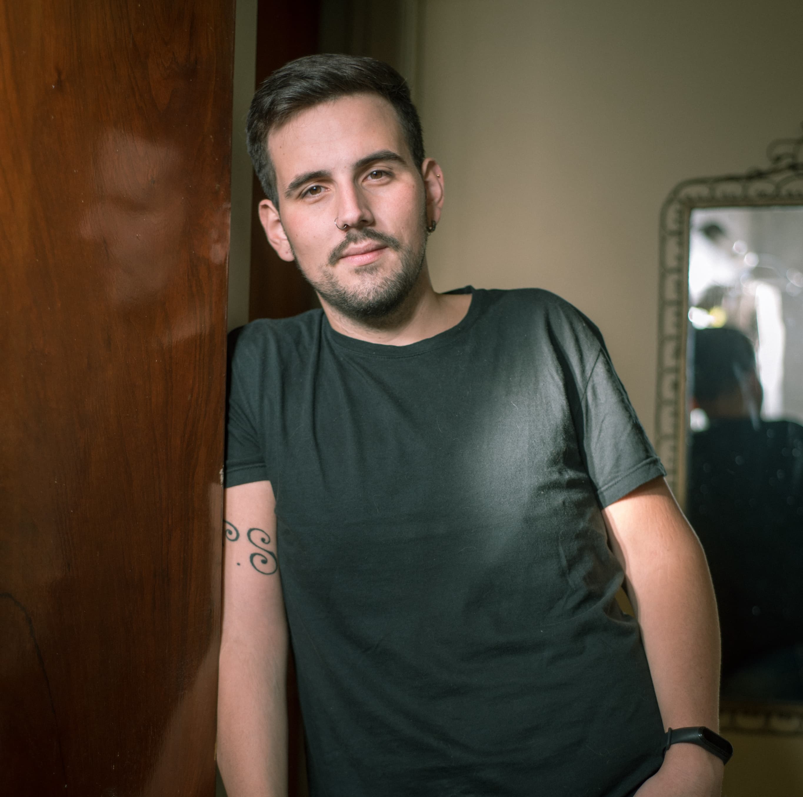 Julian standing and leaning against a door